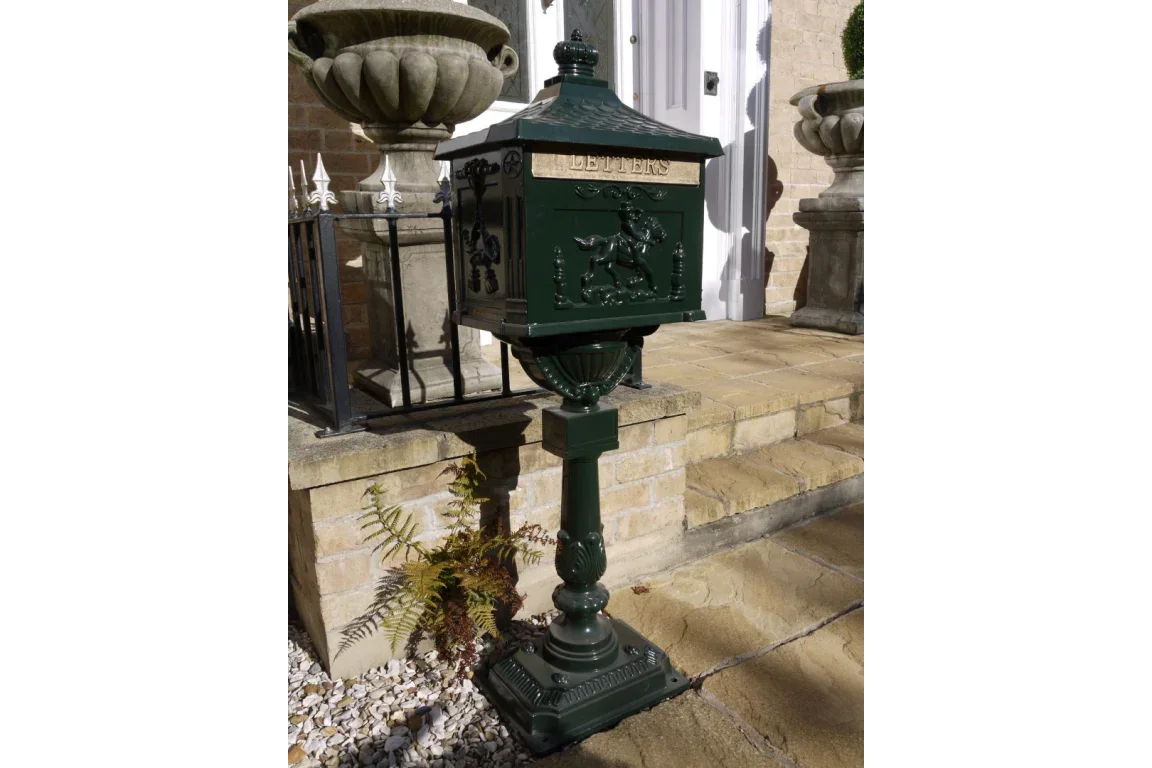 Green cast iron post box with embossed horse design on pedestal by front steps