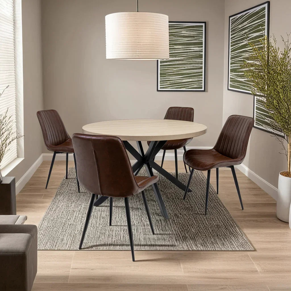 Round dining table with black legs and four brown leather chairs in modern dining room