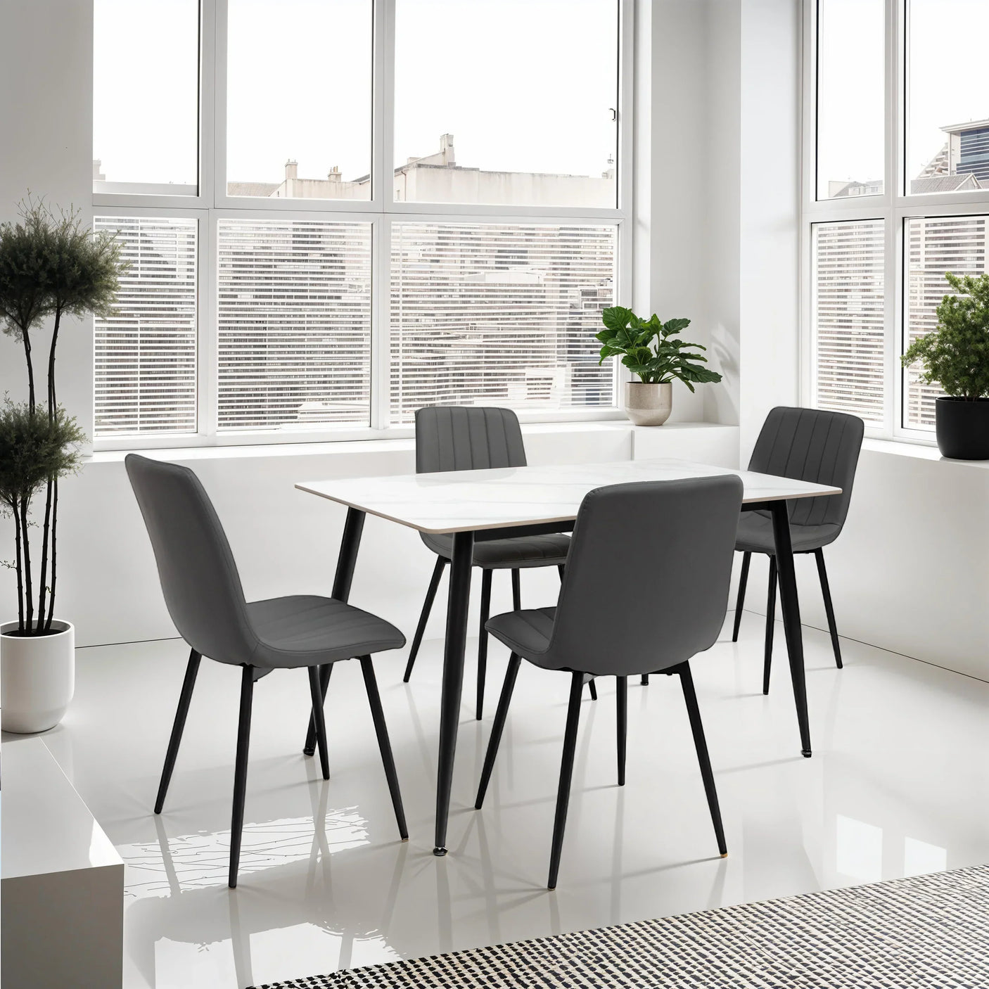 Modern dining table set with four grey padded chairs in bright room with large windows