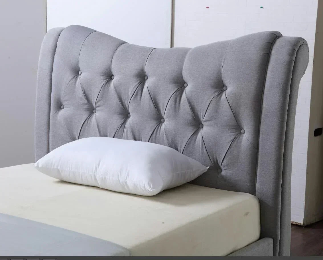 Grey upholstered bed with button tufted headboard and white pillow