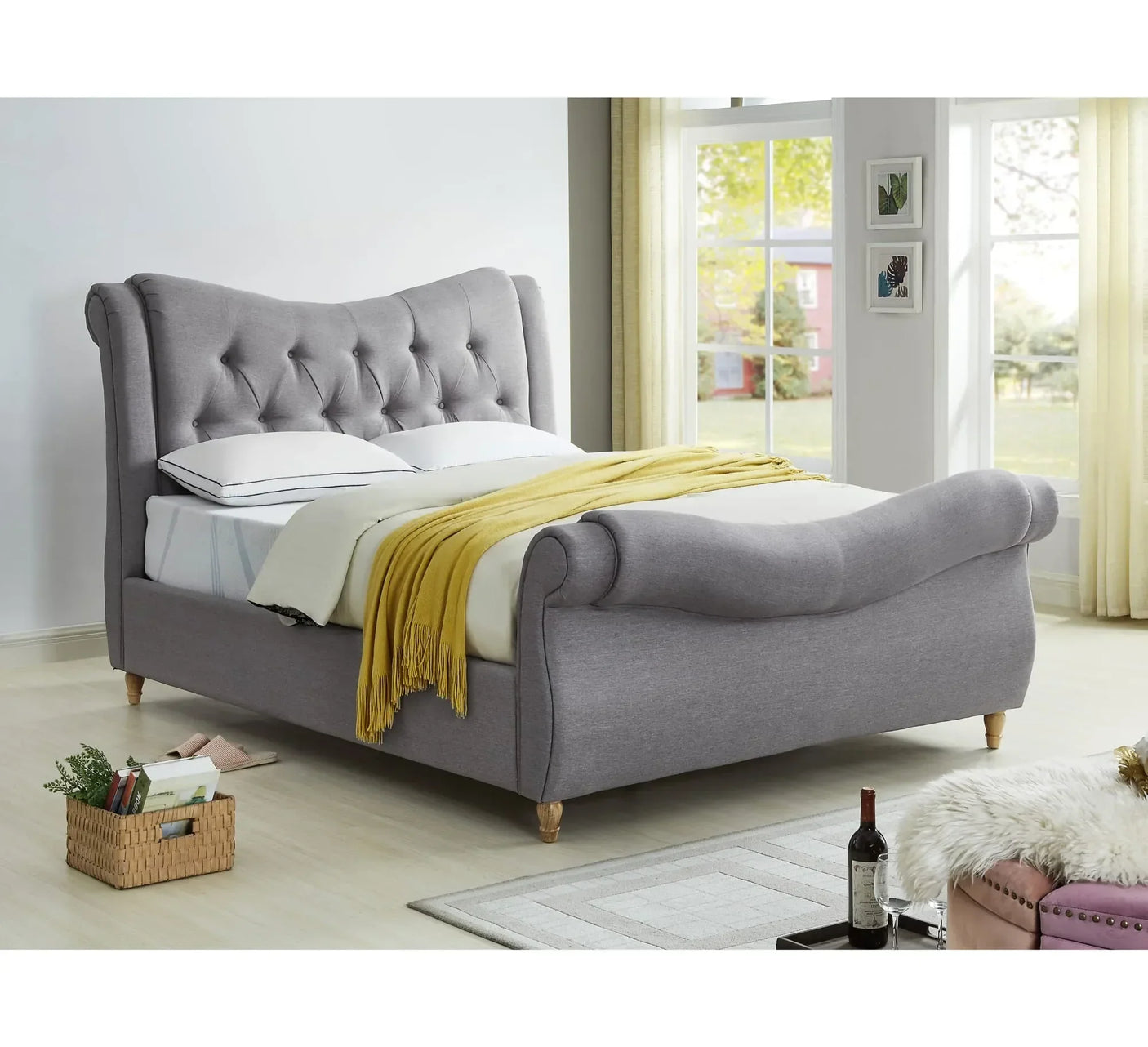 Grey upholstered sleigh bed with tufted headboard in bright bedroom setting