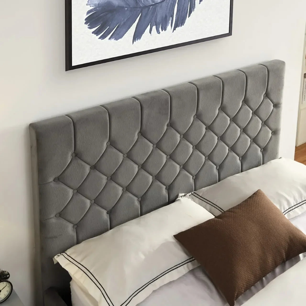 Grey upholstered bed headboard with diamond tufting, shown with white bedding and cushions