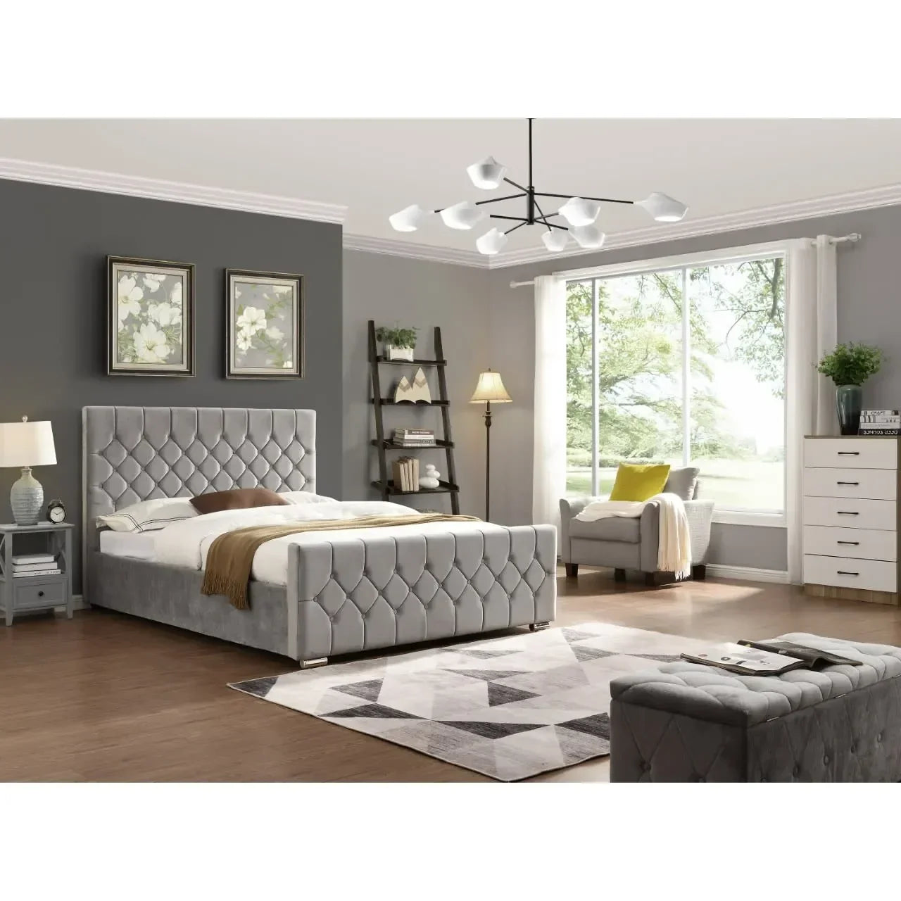 Grey upholstered bed with tufted headboard in modern bedroom with armchair and ladder shelf