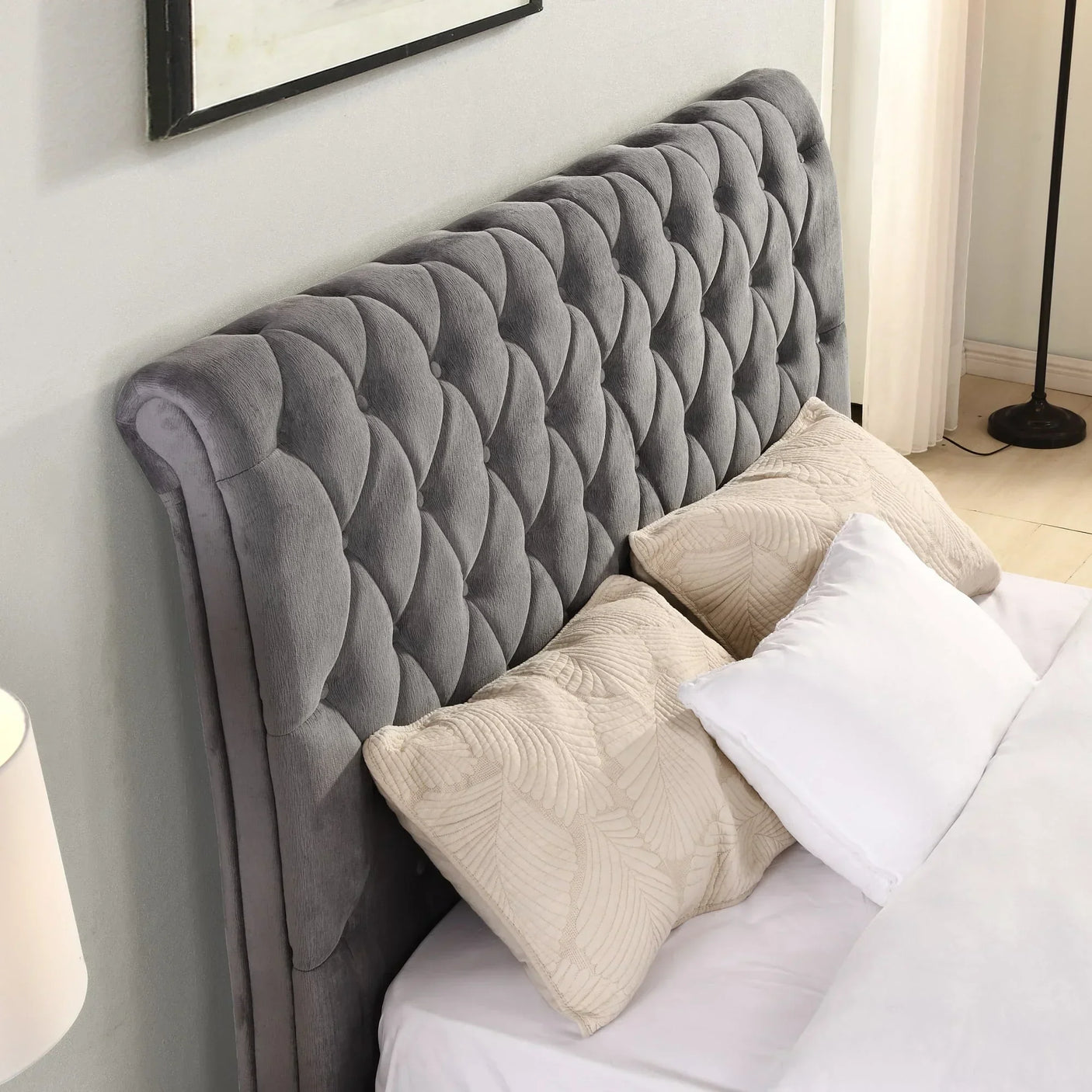 Grey upholstered bed frame with button tufted headboard and beige cushions