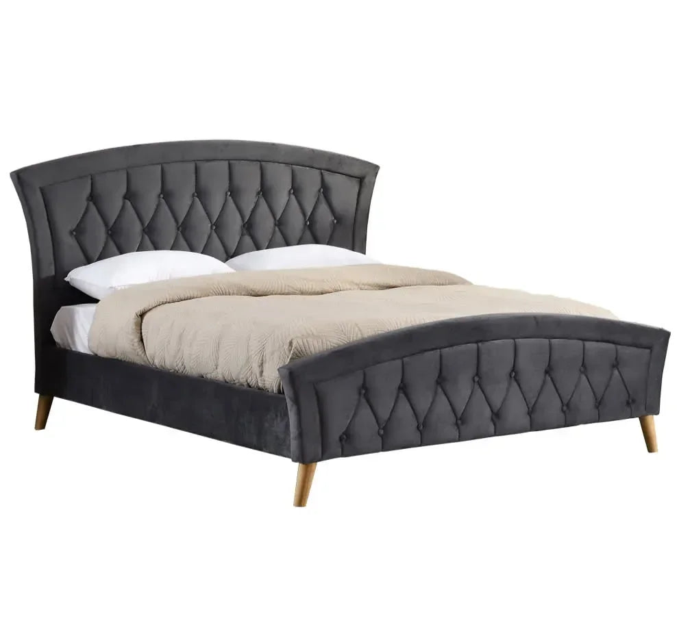 Grey upholstered bed frame with tufted headboard and wooden legs, dressed with bedding
