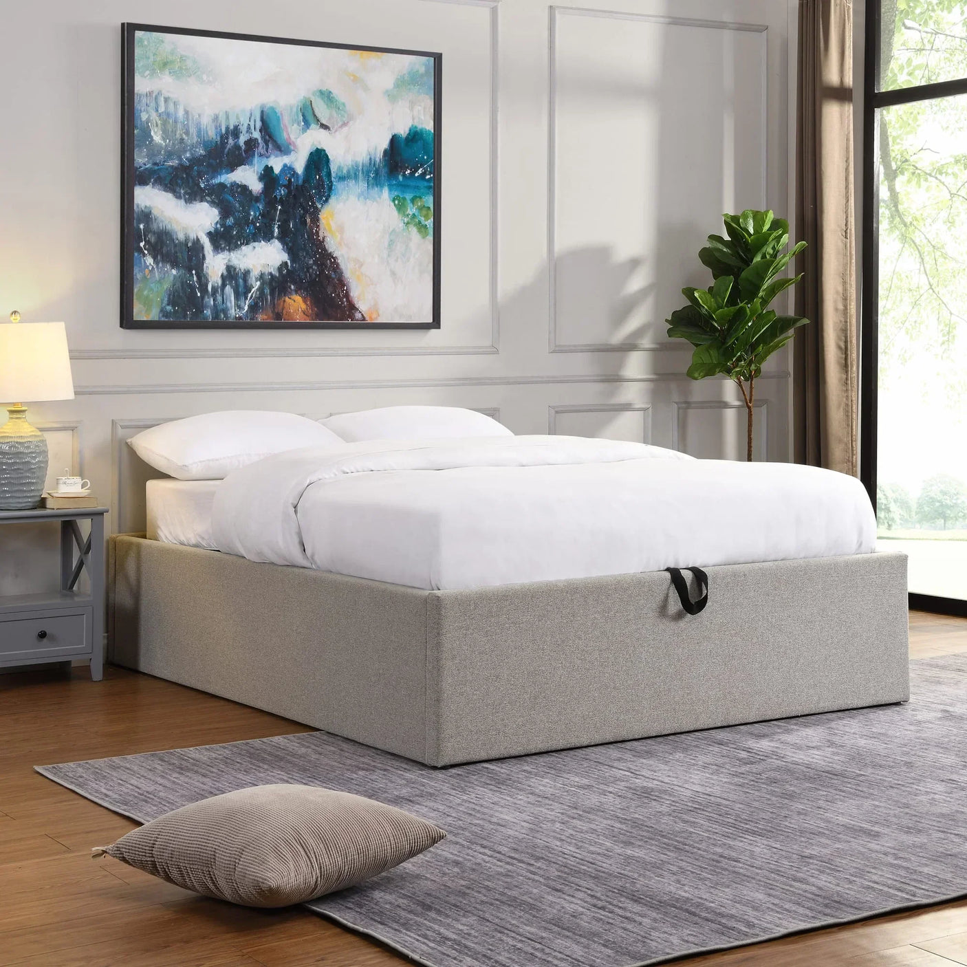 Grey upholstered ottoman storage bed with white bedding in a bright modern bedroom