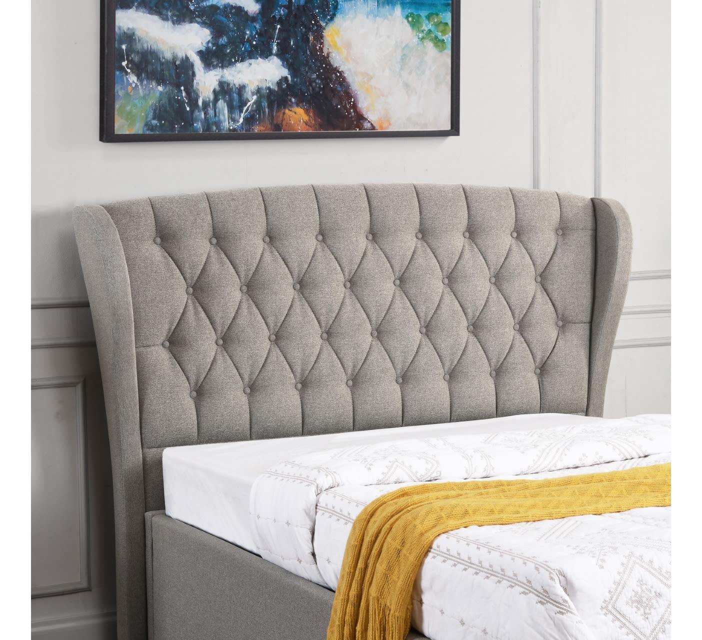 Grey upholstered bed with tufted headboard, yellow blanket, modern wall art above