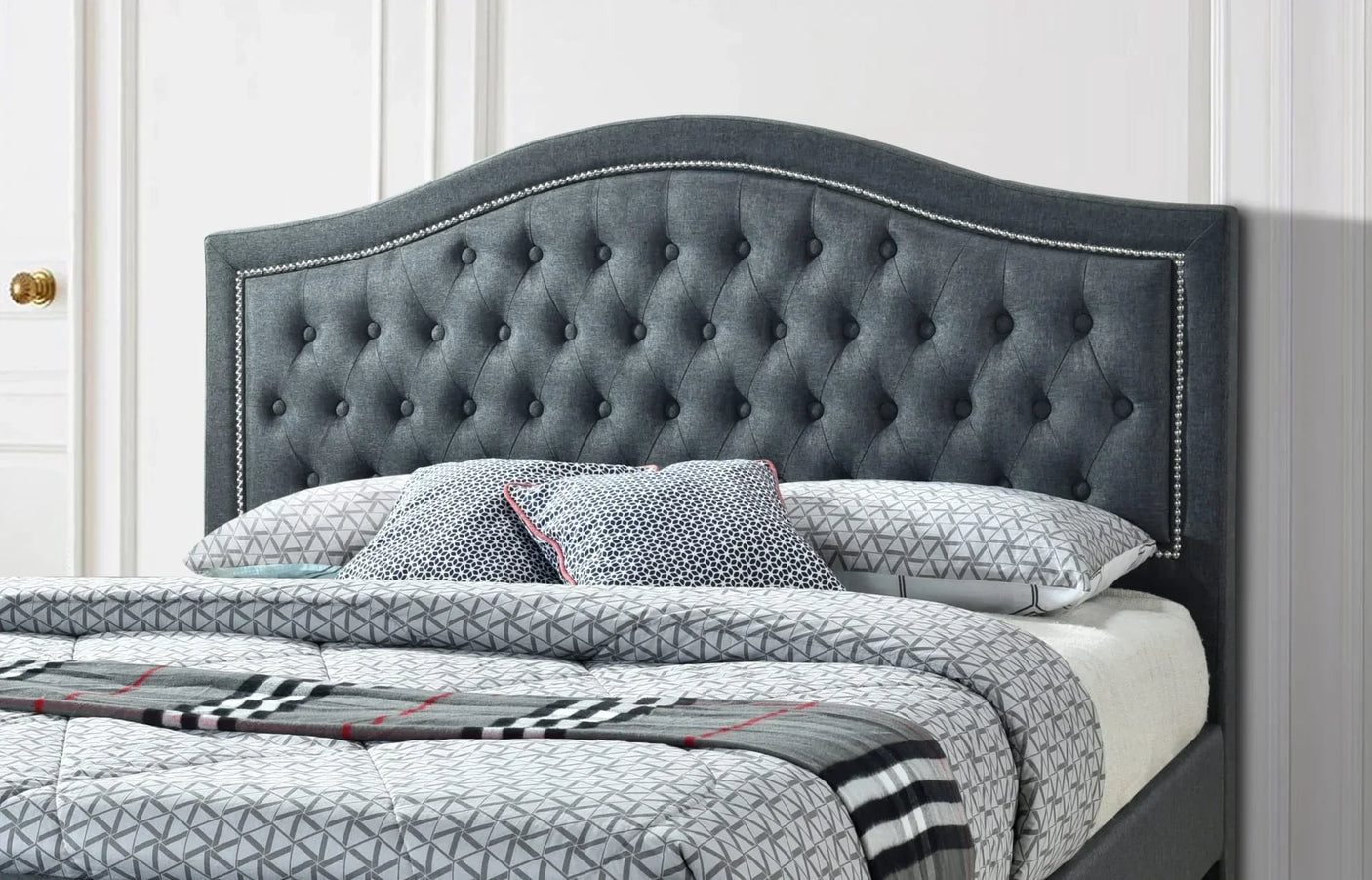 Dark grey upholstered bed frame with button-tufted headboard and geometric bedding