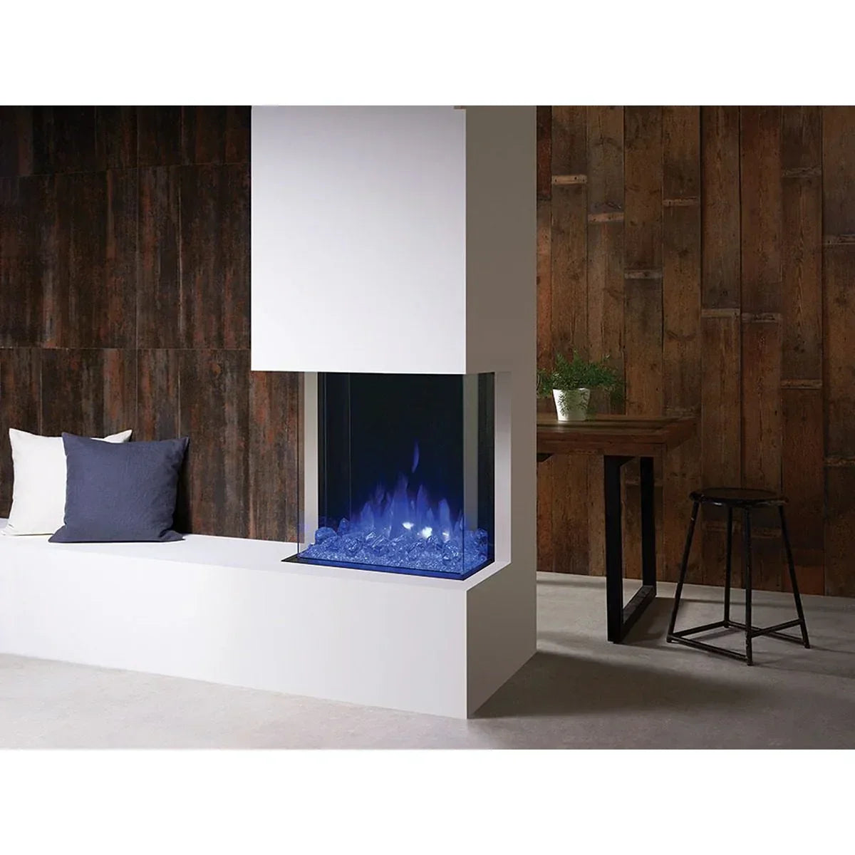 Modern electric fireplace with blue flame, white frame, wood panel wall, bench and table