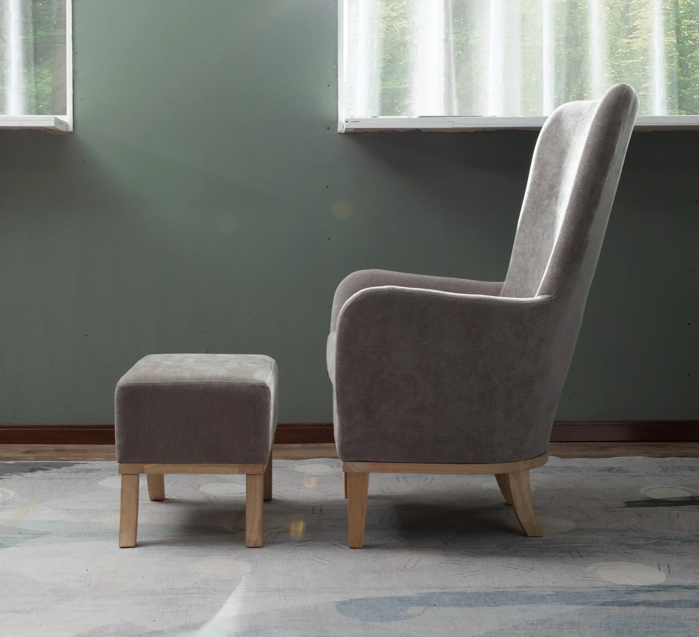 Grey fabric armchair with matching footstool on wooden legs, side view