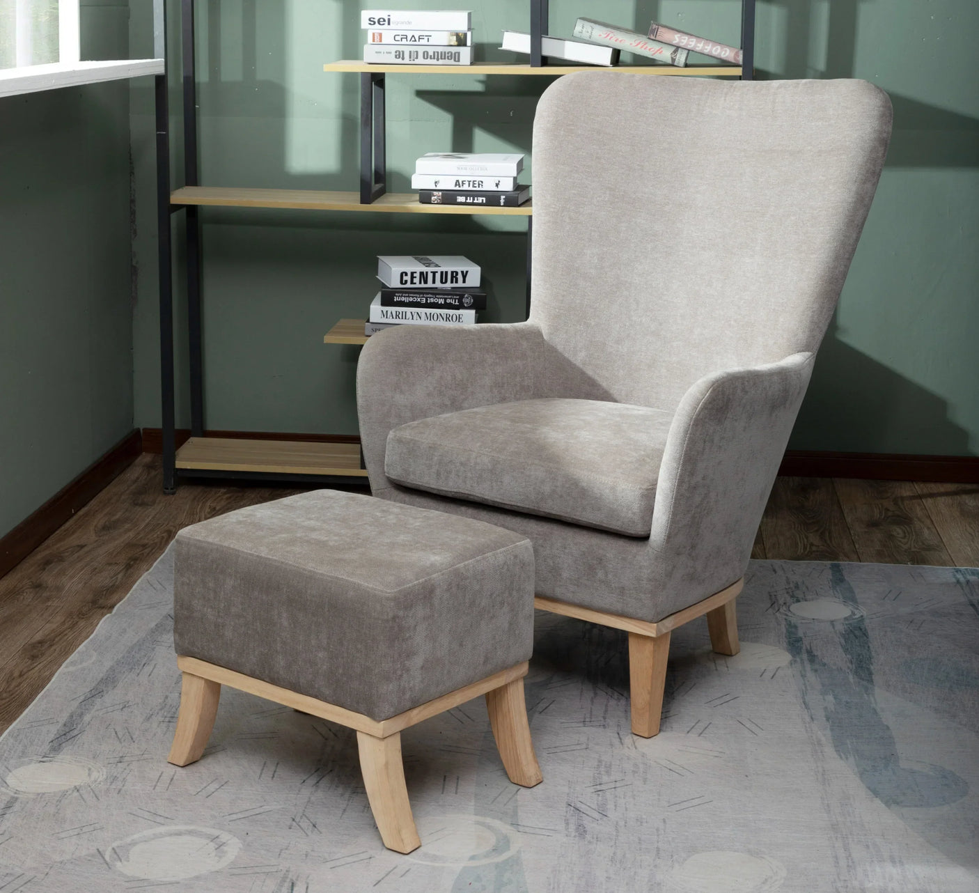 Light grey upholstered armchair with wooden legs and matching footstool on patterned rug