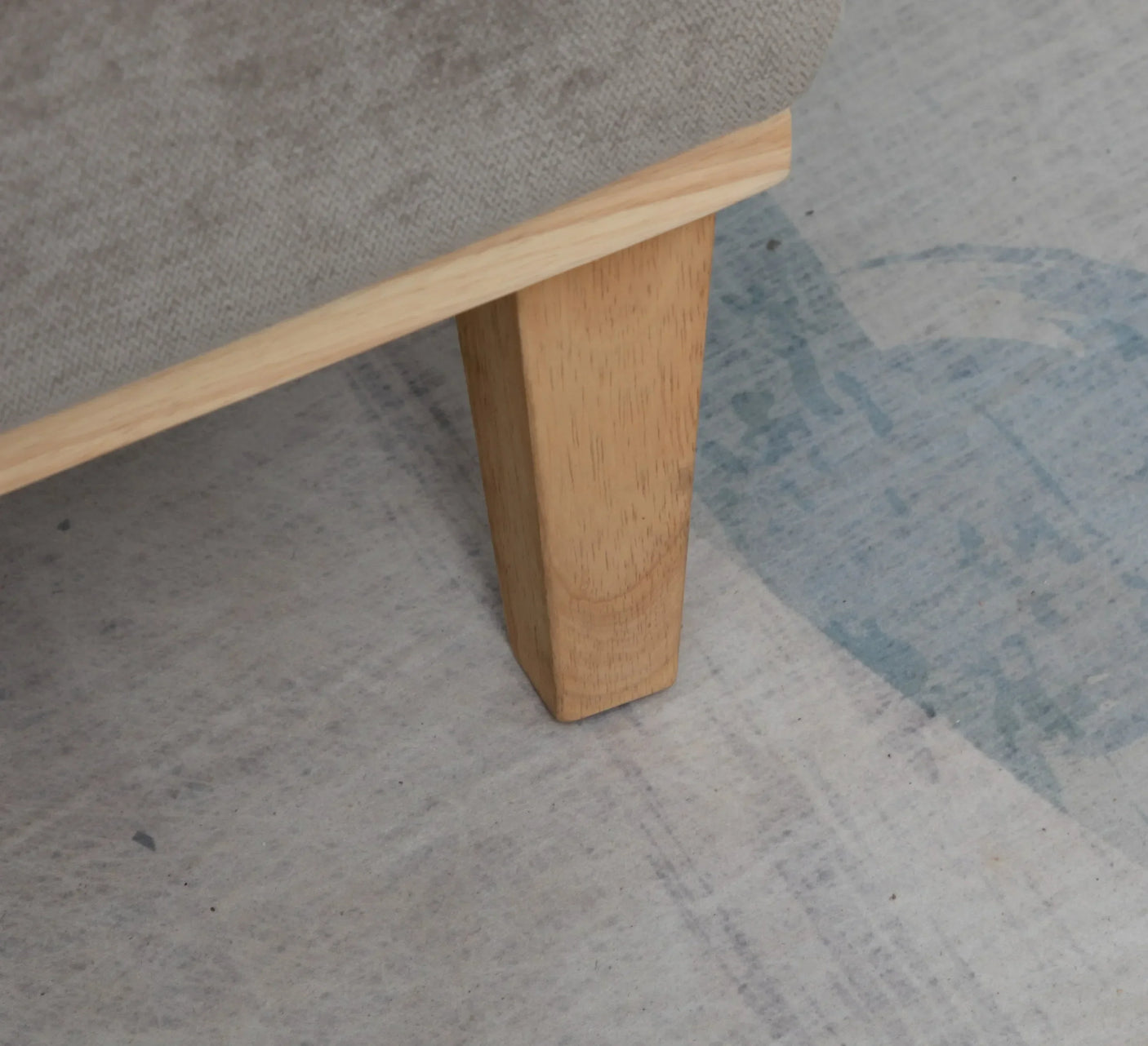 Light wood sofa leg on neutral carpet close-up