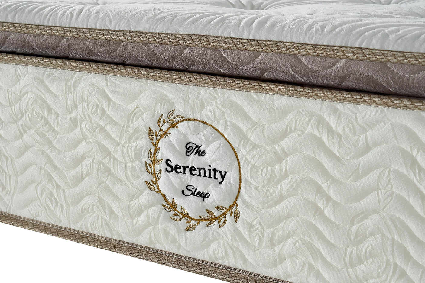 Closeup of Serenity Sleep mattress with quilted white fabric and gold embroidery