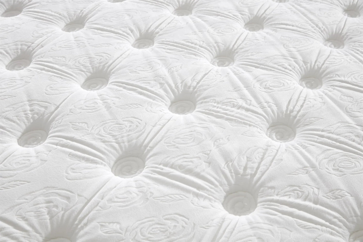 Close-up of tufted mattress surface with floral pattern and white fabric texture