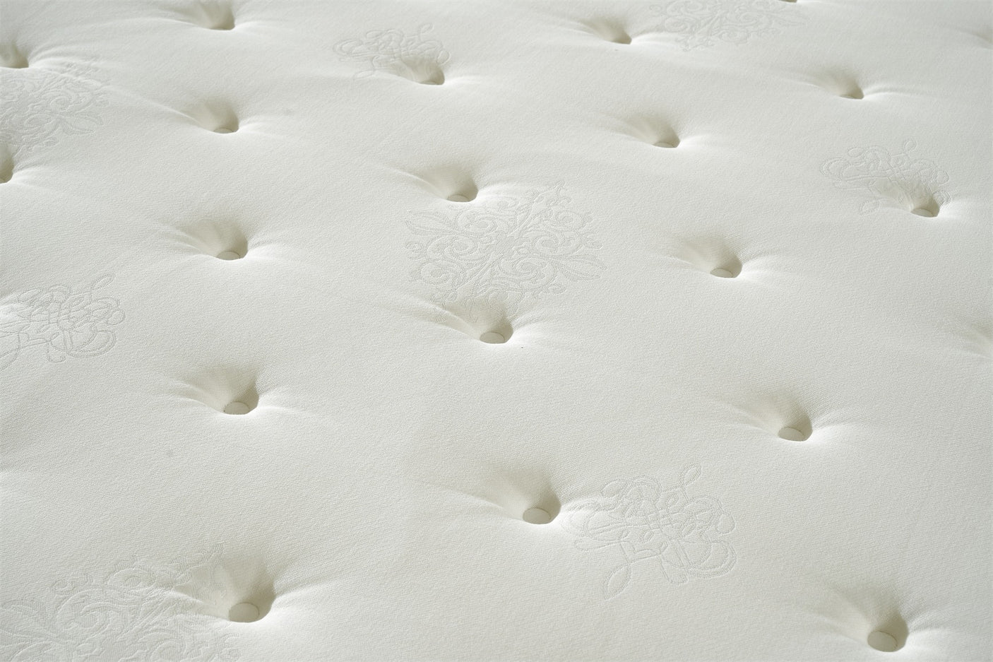 Close up of cream mattress surface with button tufting and subtle embroidered pattern