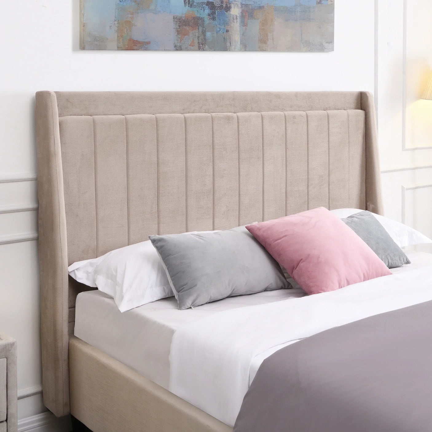 Beige upholstered bed with vertical panel headboard and pastel velvet cushions