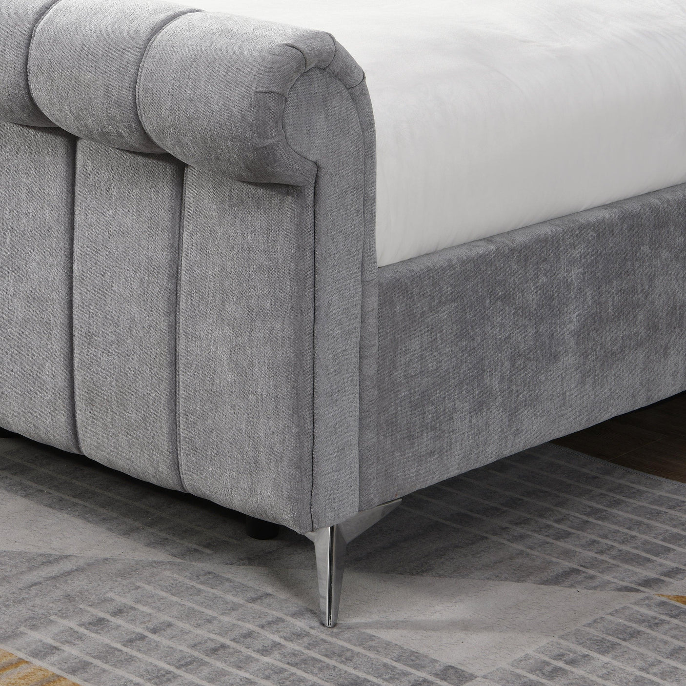 Grey upholstered bed with metal legs and vertical panel headboard on patterned rug