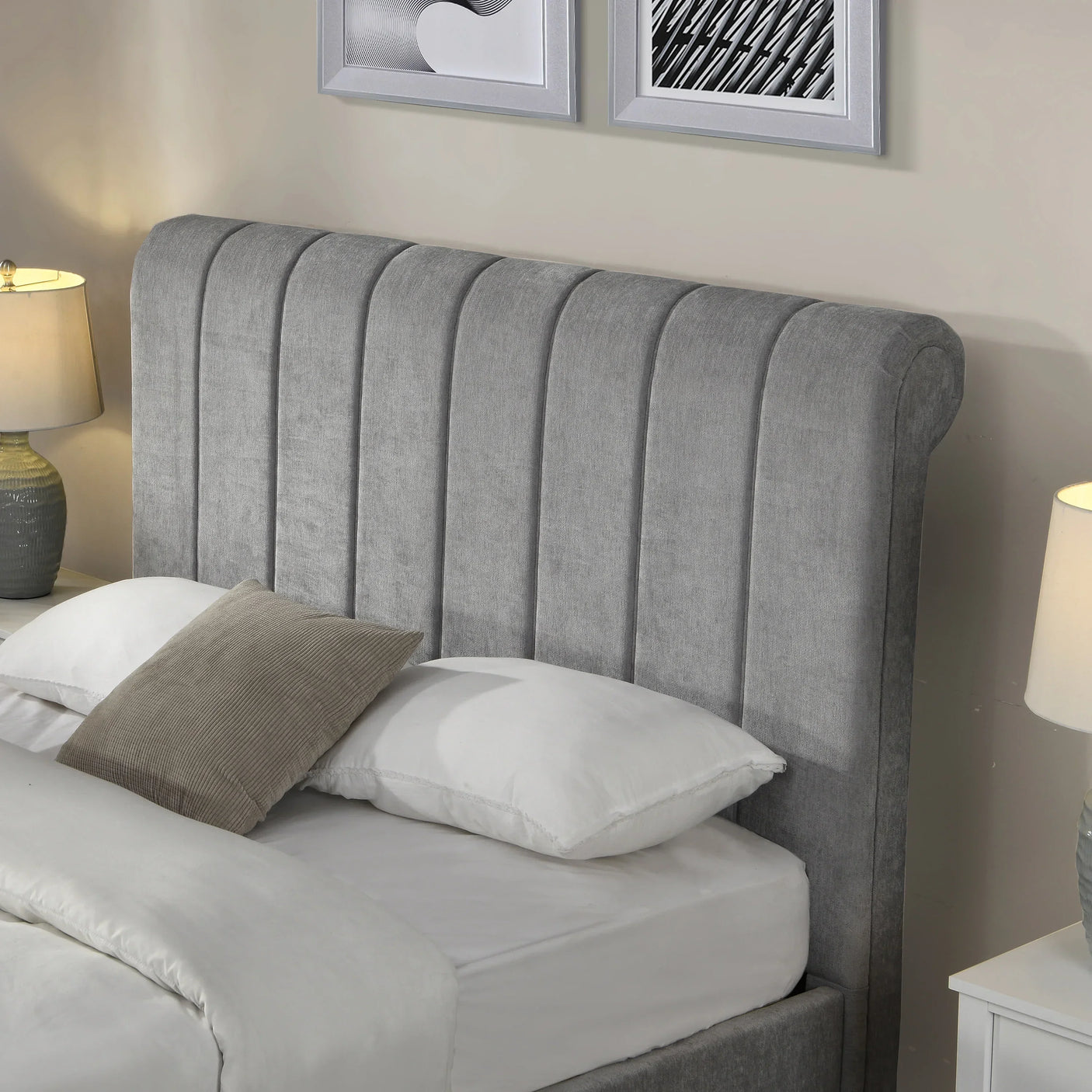 Grey upholstered bed with vertical panel headboard, white bedding, and bedside lamps