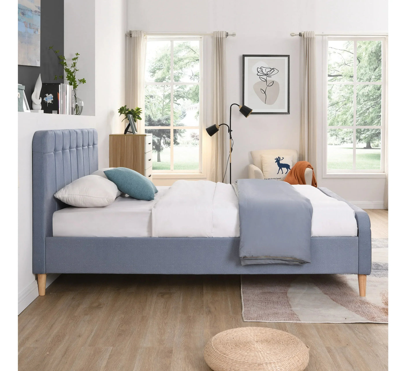 Light blue upholstered bed frame with padded headboard in bright modern bedroom setting