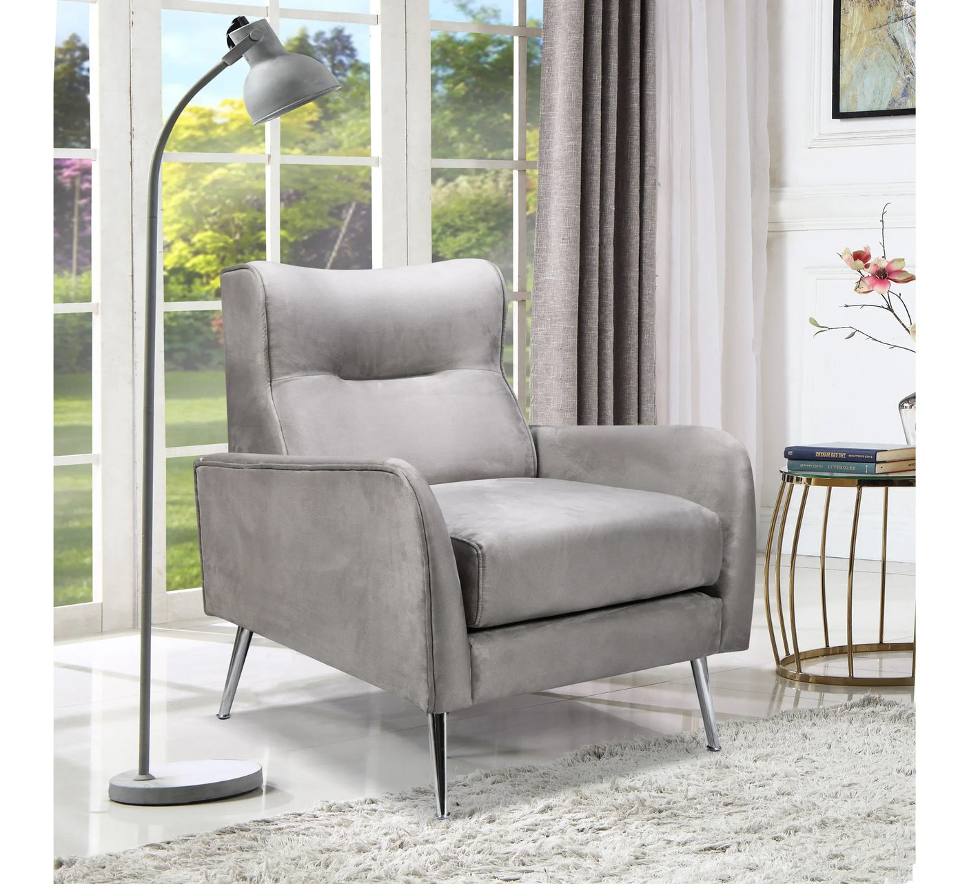 Grey velvet accent chair with metal legs in modern living room by window and floor lamp
