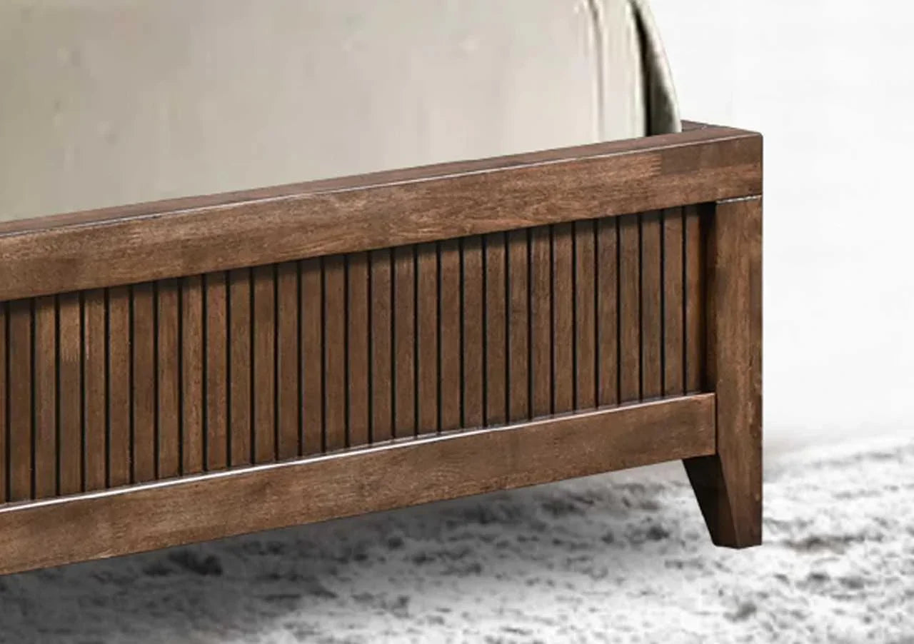 Wooden bed frame with slatted panel footboard on textured rug