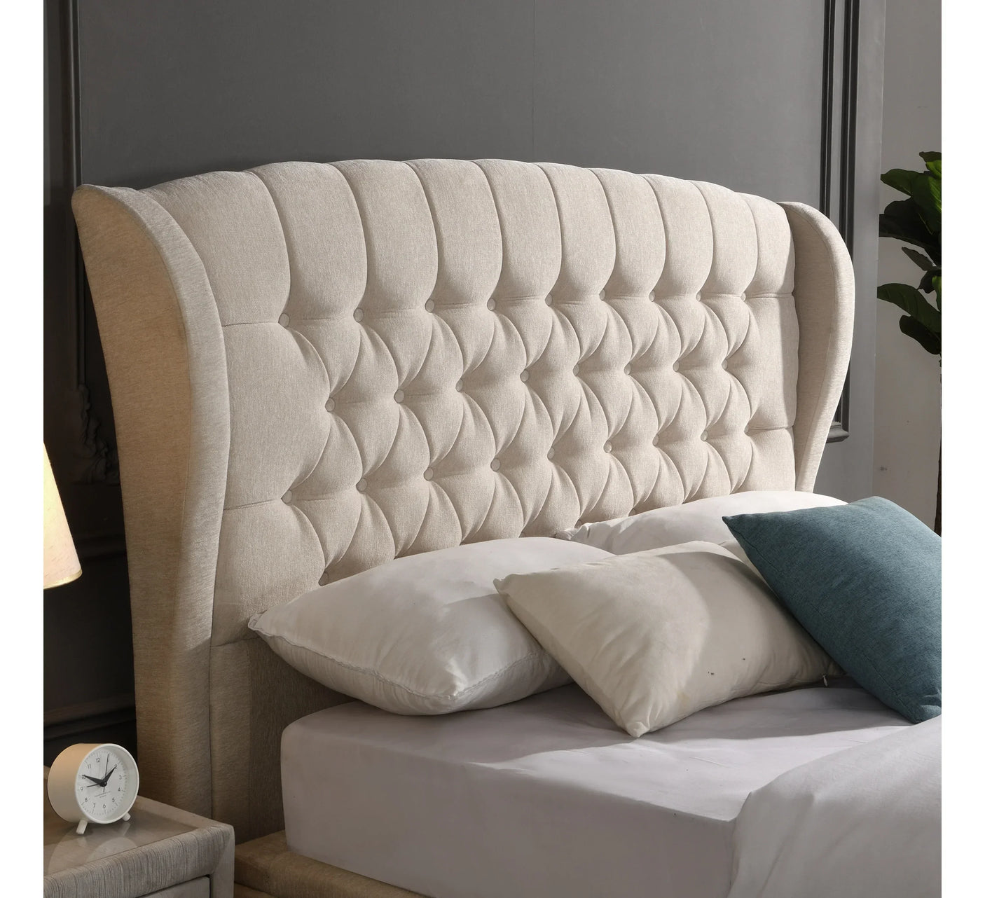 Beige upholstered bed with tufted headboard, cream and blue cushions, modern bedroom decor