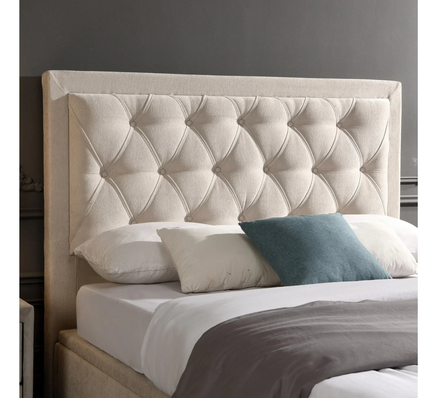 Cream fabric upholstered bed with button tufted headboard and accent pillows