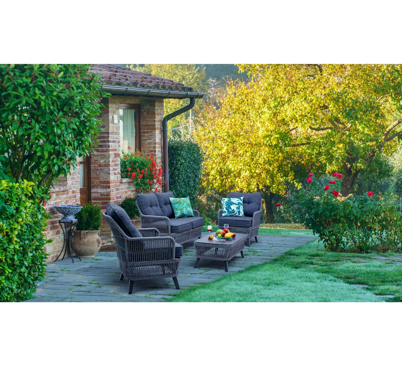 Grey rattan garden furniture set with cushions and coffee table on stone patio