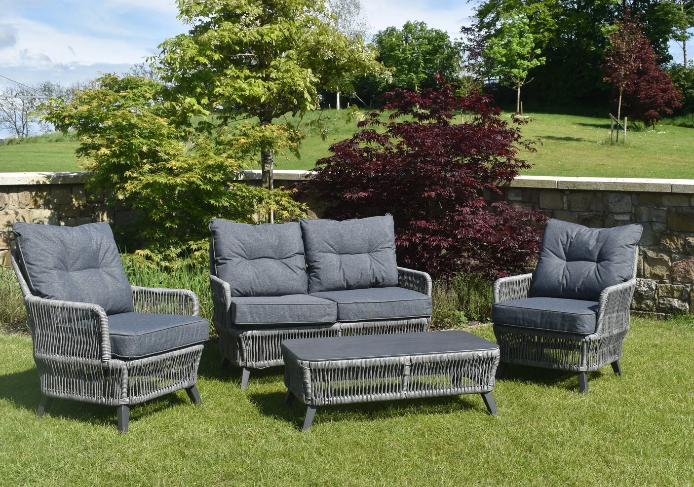 Grey rattan garden furniture set with cushions and coffee table on lawn