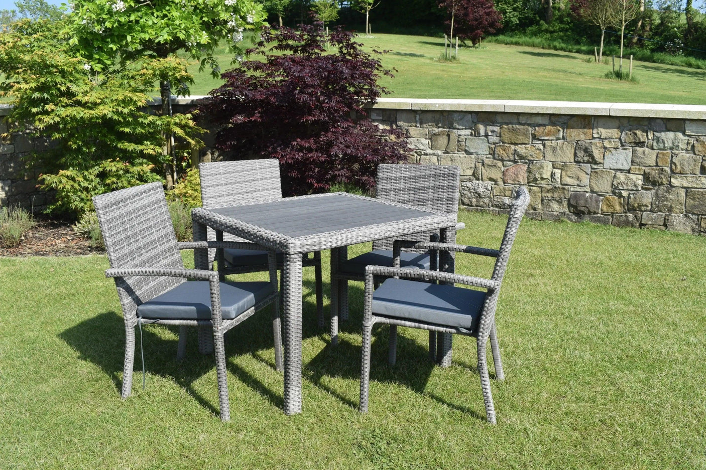 Grey rattan garden dining set with four chairs and square table on lawn