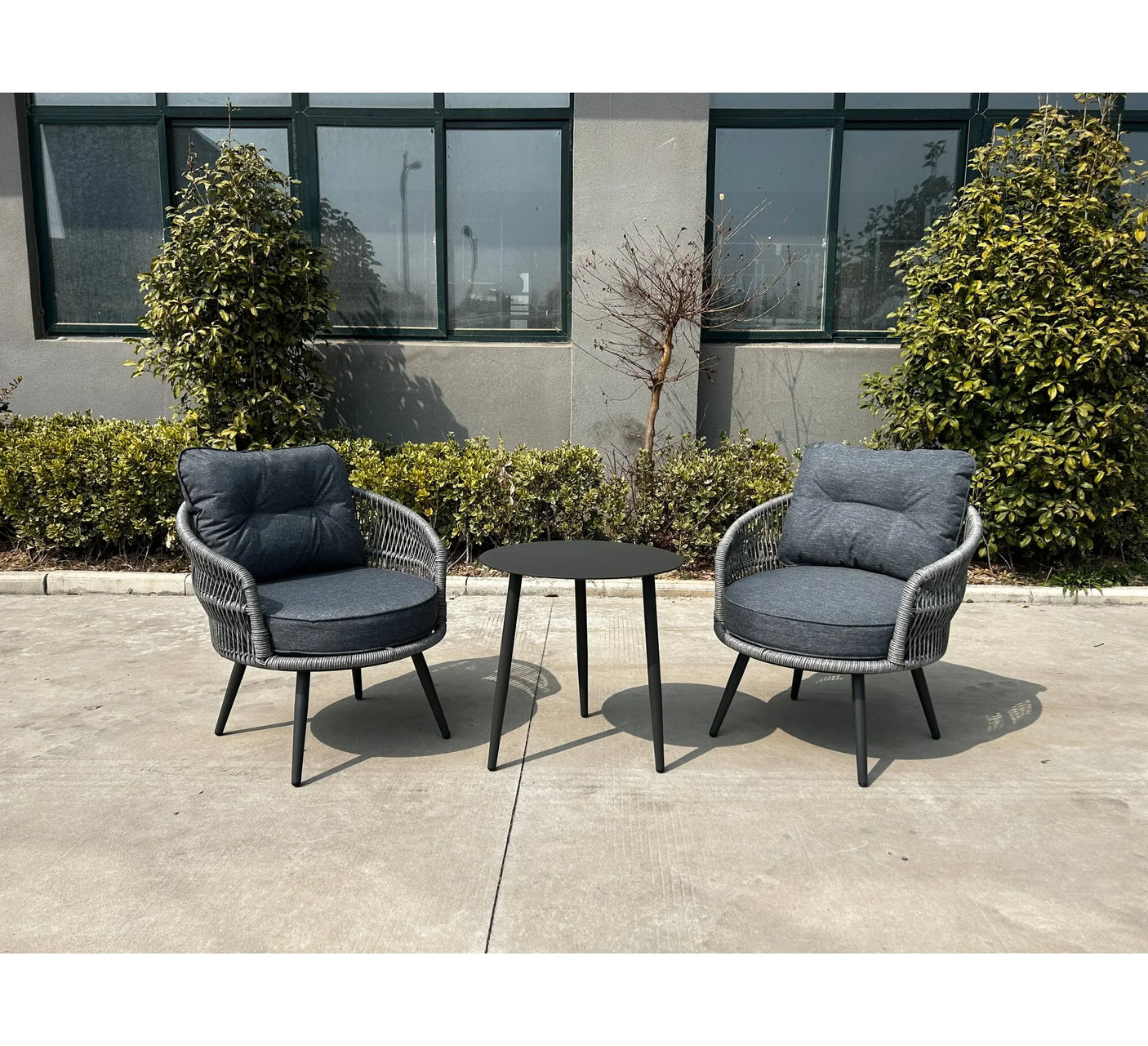 Grey rattan garden furniture set with two cushioned chairs and round table on patio