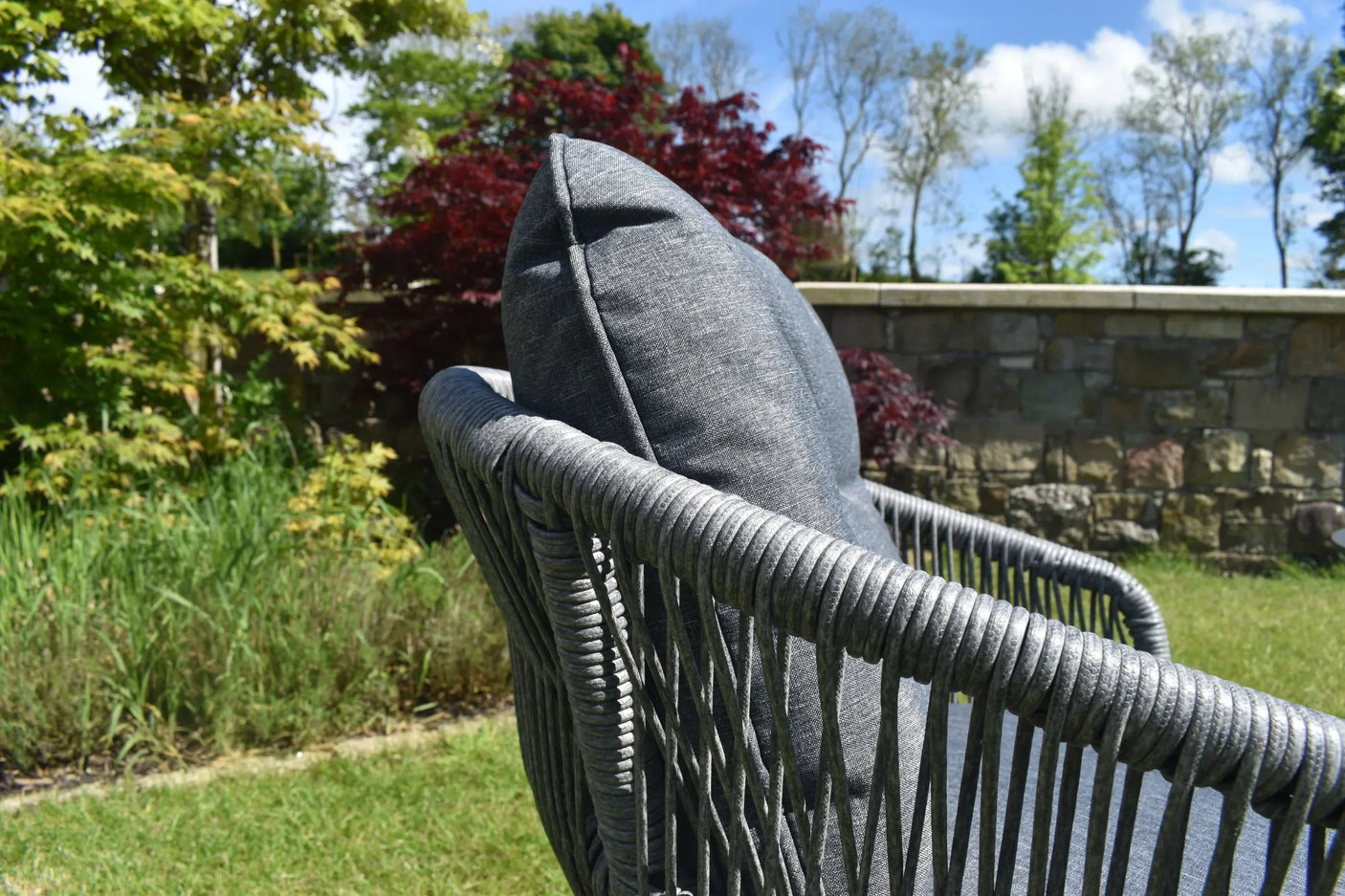 Closeup of grey rattan garden sofa with cushion in outdoor patio setting
