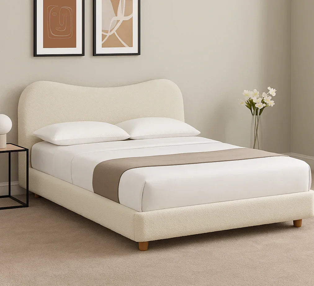 Cream upholstered bed frame with curved headboard, white bedding, and wooden legs in modern bedroom