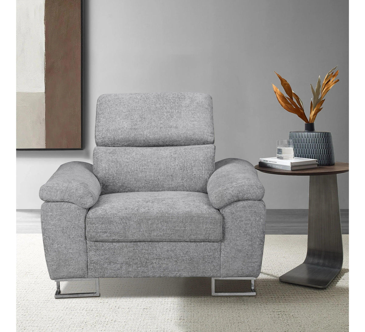 Grey fabric armchair with metal legs beside side table and decorative vase in modern living room