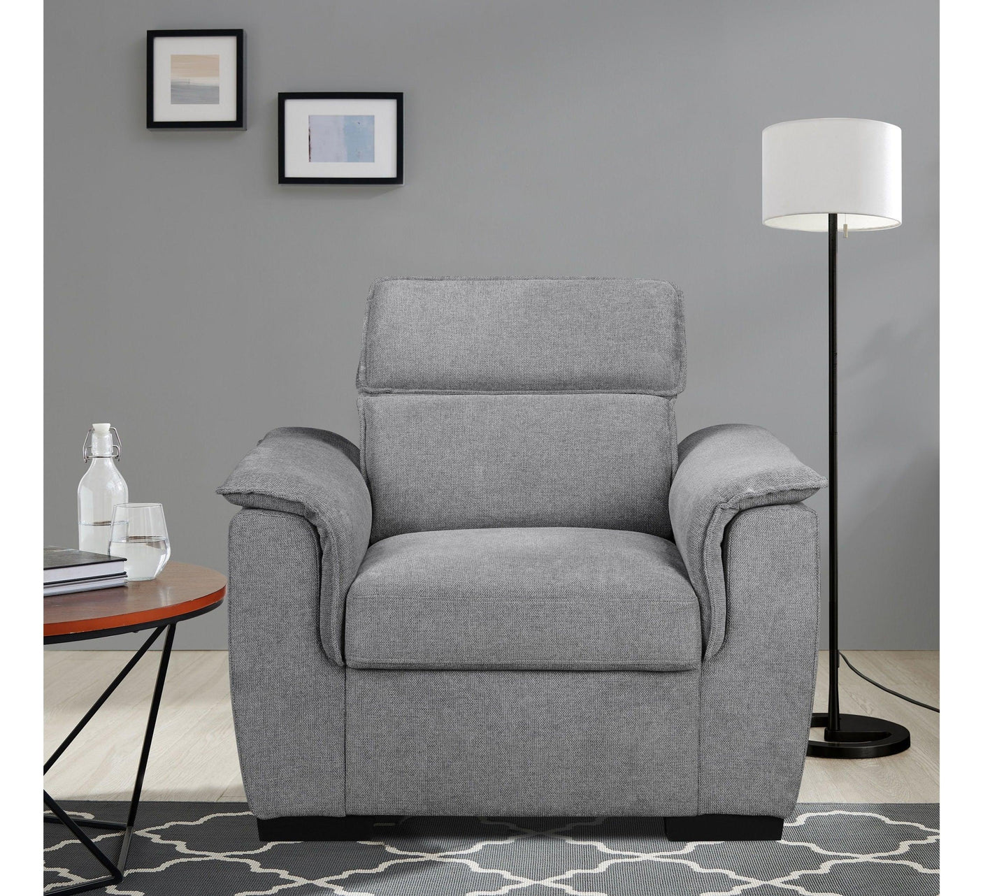 Grey fabric armchair with cushioned arms in living room, side table and floor lamp nearby