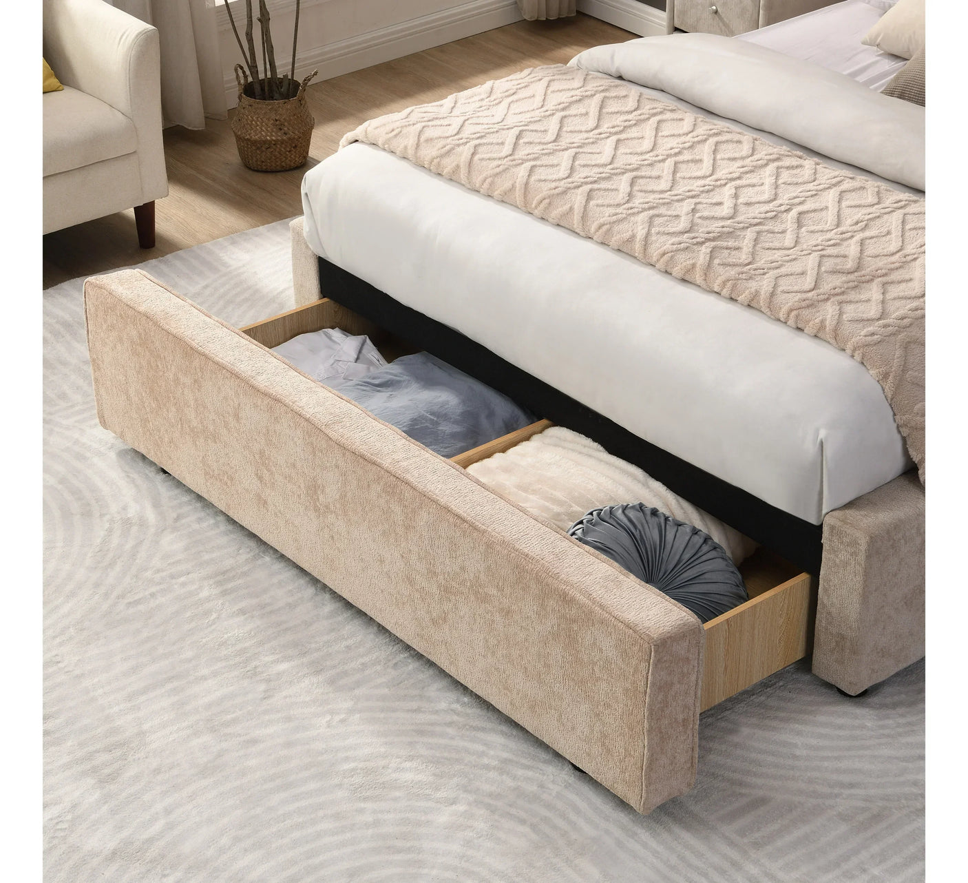 Beige upholstered storage bed with open footboard drawer holding bedding and cushions