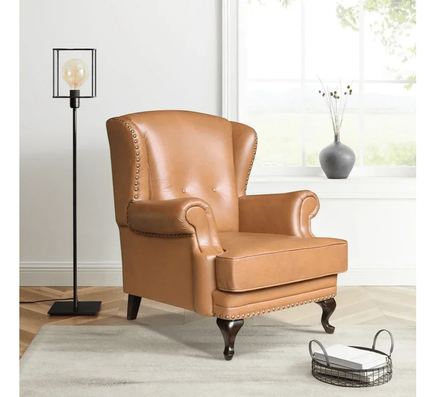 Tan leather armchair with button back and stud details in bright living room setting