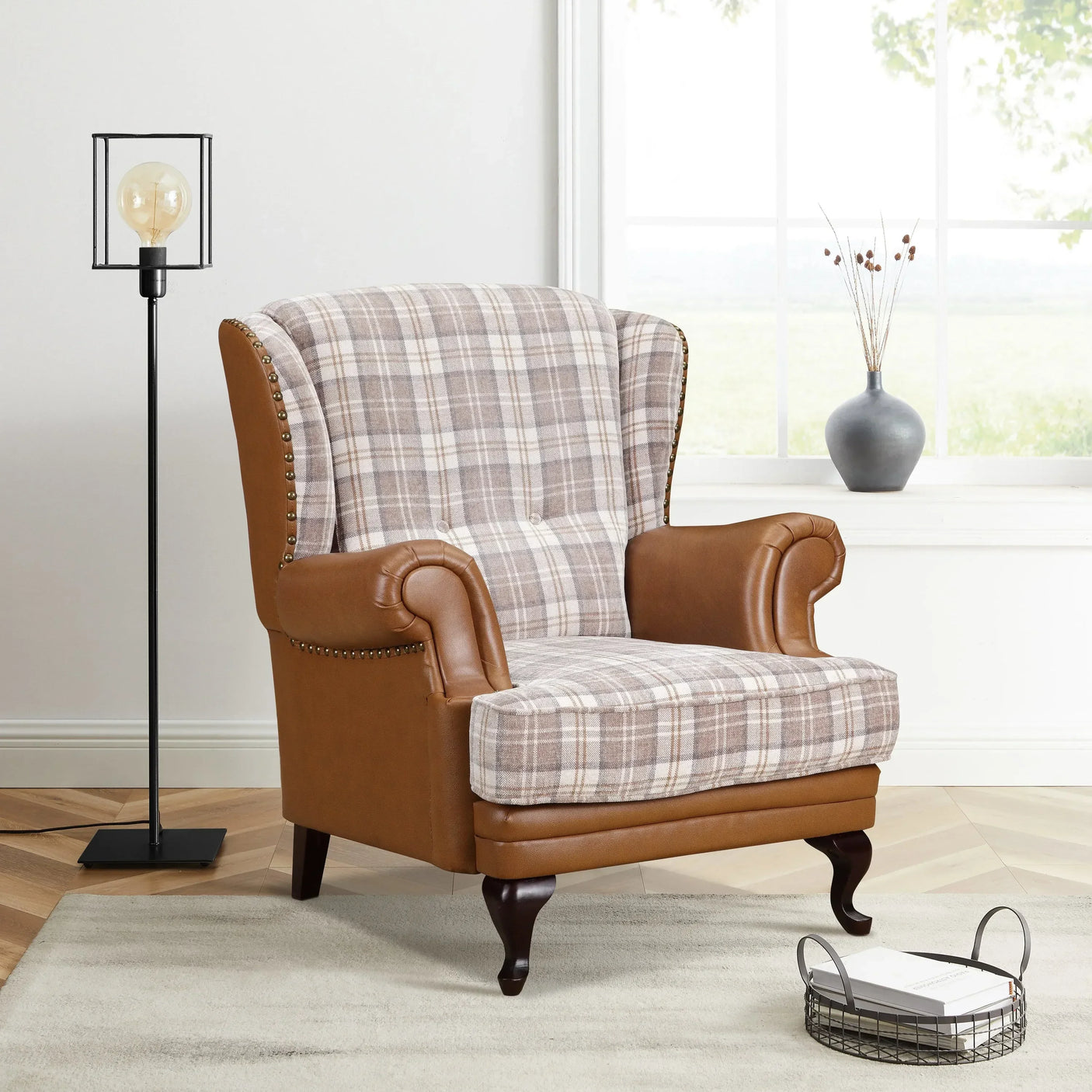 Plaid wingback armchair with brown leather accents in bright living room