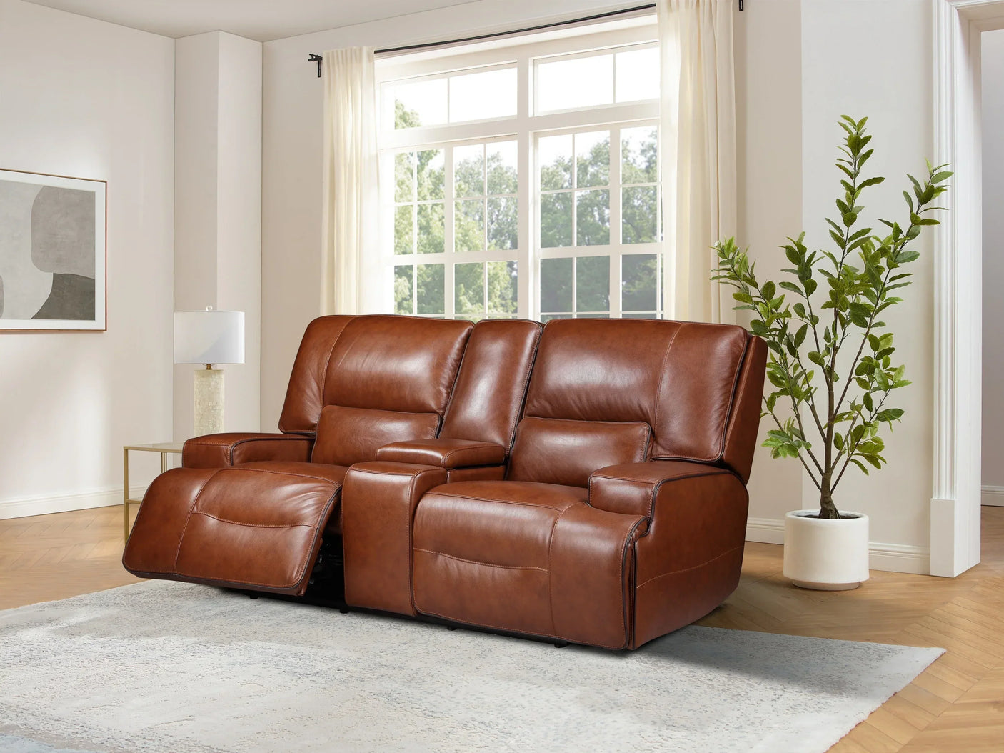Brown leather recliner sofa with center console in bright living room with plant