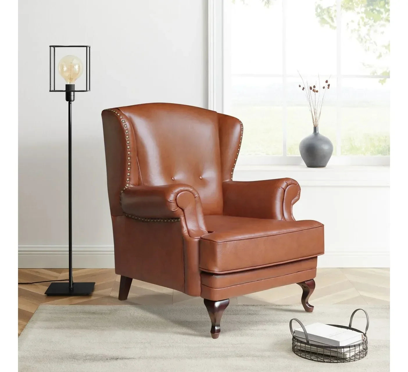 Brown leather armchair with studded details in living room next to modern floor lamp