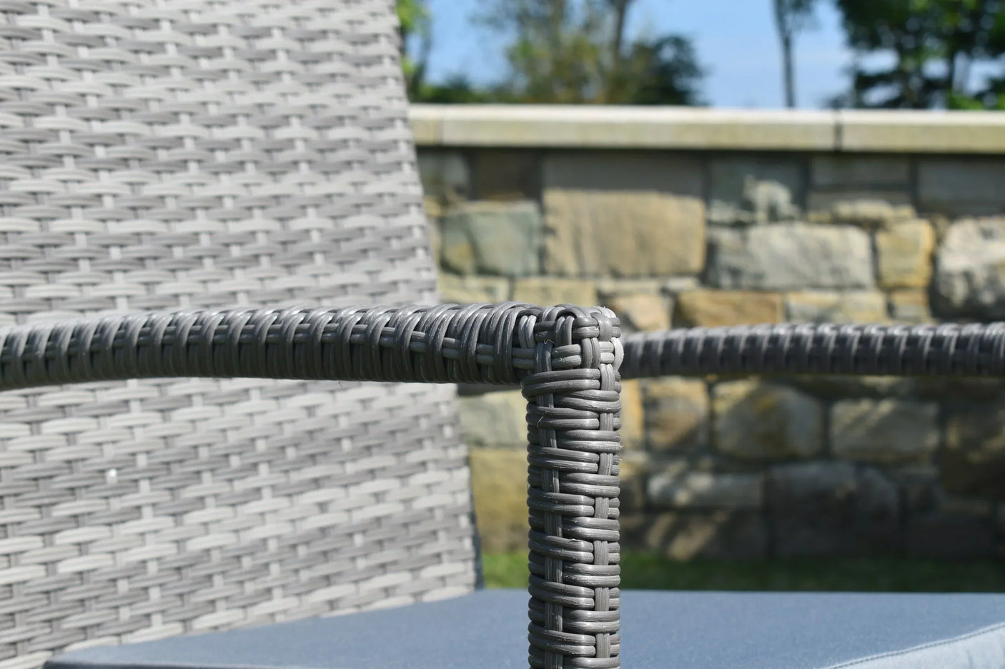 Grey rattan garden chair armrest and woven backrest close-up
