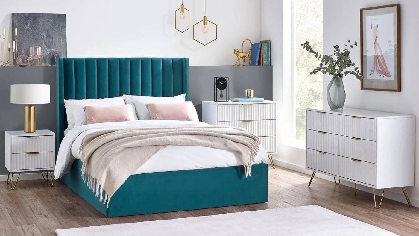 Teal upholstered bed frame with white ribbed bedside tables and gold accents in modern bedroom
