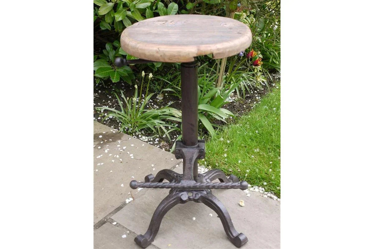 Industrial bar stool with round wooden seat and cast iron base on garden patio