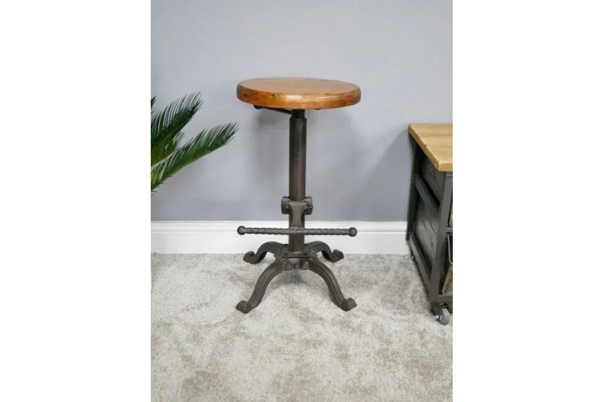 Industrial bar stool with round wooden seat and black metal base on carpeted floor