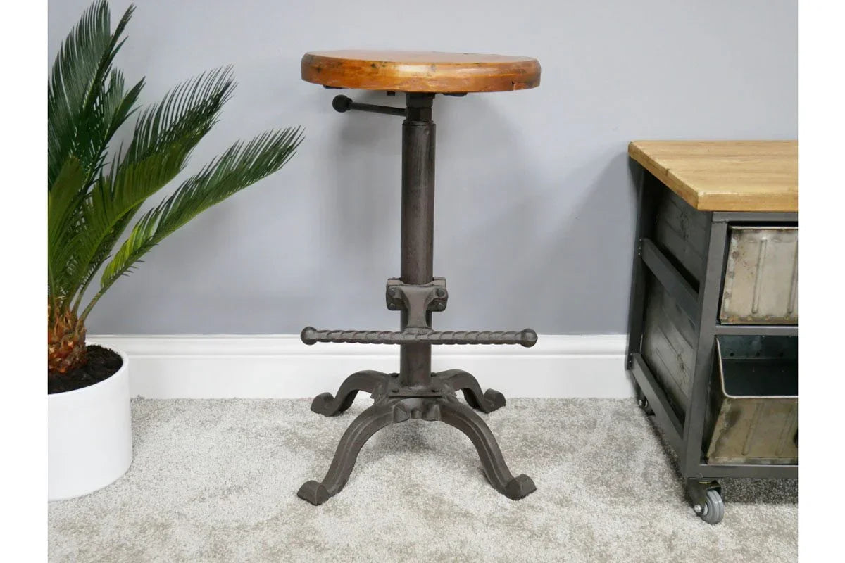 Industrial bar stool with round wooden seat and black metal base on carpeted floor