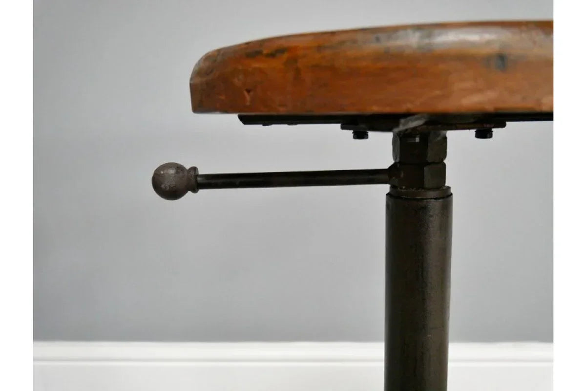 Industrial bar stool with round wooden seat and metal height adjustment lever