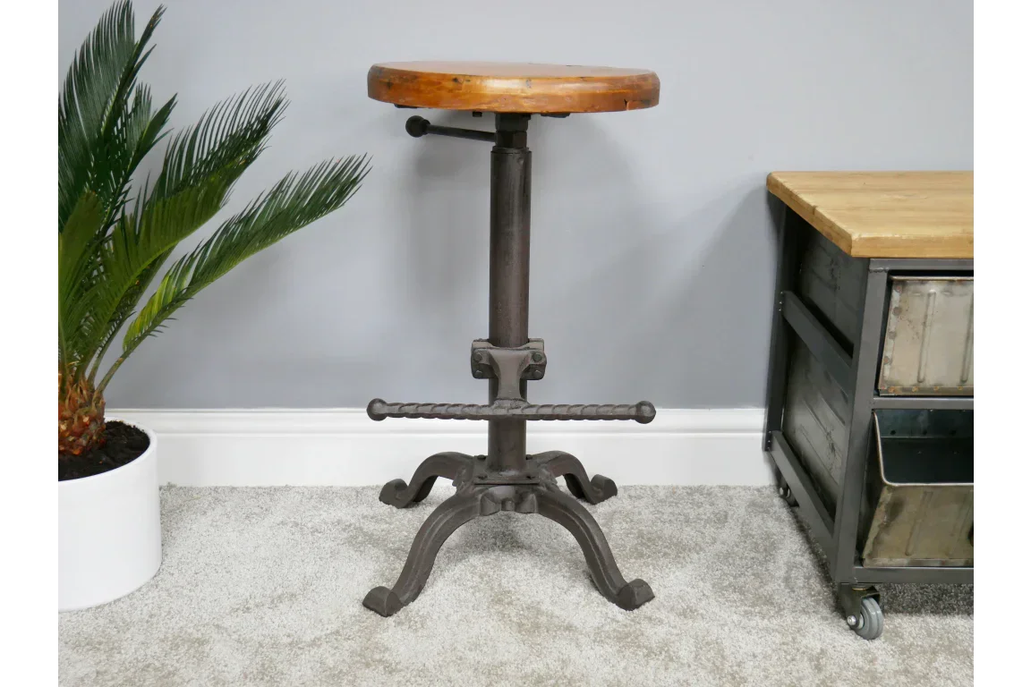 Industrial bar stool with round wooden seat and cast iron base on carpeted floor