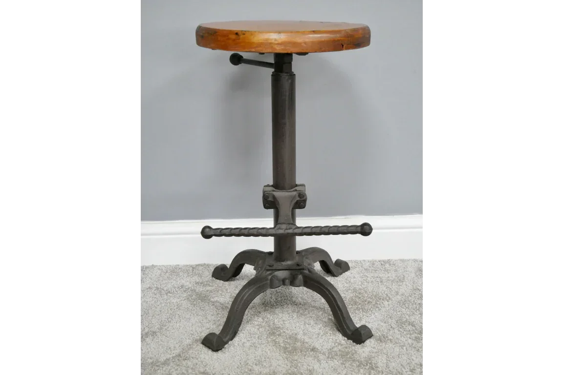 Industrial style bar stool with round wooden seat and black metal base on grey carpet