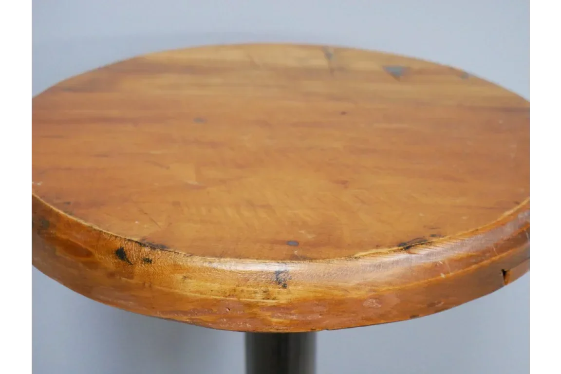 Round wooden stool seat with visible grain and rustic finish, close-up side angle