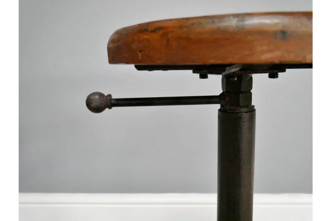 Closeup of wooden adjustable stool seat with visible metal height adjustment lever